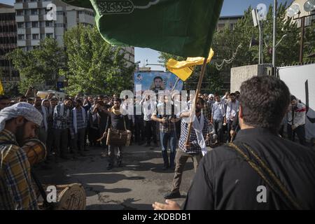 Un gruppo di studenti universitari iraniani Basiji (membri della forza paramilitare Basij) sventola bandiere e suona strumenti musicali tradizionali di fronte a un ritratto del comandante della Guardia rivoluzionaria islamica assassinato, il colonnello Sayyad Khodai, Nel corso di un rally in occasione del trentatreesimo anniversario di morte del Fondatore della Repubblica Islamica, Ayatollah Ruhollah Khomeini, di fronte alla porta principale dell'Università di Teheran (non raffigurata) il 3 giugno 2022. (Foto di Morteza Nikoubazl/NurPhoto) Foto Stock