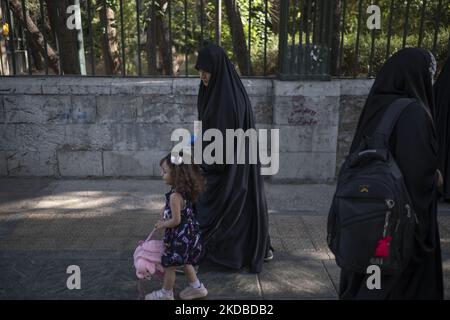 Una donna iraniana Basiji (membri della forza paramilitare Basij) velata cammina con la sua giovane figlia quando arrivano all'università di Teheran per partecipare a un raduno per celebrare il trentatreesimo anniversario di morte del fondatore della Repubblica islamica, Ayatollah Ruhollah Khomeini, 3 giugno 2022. (Foto di Morteza Nikoubazl/NurPhoto) Foto Stock