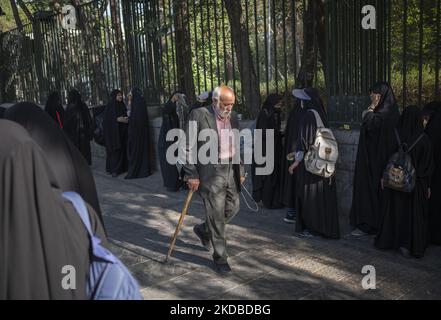 Un uomo anziano passa davanti a studenti universitari iraniani Basiji (membri della forza paramilitare Basij) prima di un raduno per celebrare il trentatreesimo anniversario di morte del fondatore della Repubblica islamica, Ayatollah Ruhollah Khomeini, fuori dall'Università di Teheran il 3 giugno 2022. (Foto di Morteza Nikoubazl/NurPhoto) Foto Stock