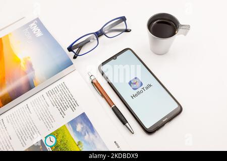 In questa foto, il logo HelloTalk viene visualizzato sullo schermo di uno smartphone su una scrivania accanto a un bar, una penna, occhiali e una rivista ad Atene, in Grecia, il 3 giugno 2022. (Foto Illustrazione di Nikolas Kokovlis/NurPhoto) Foto Stock