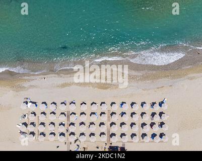 Immagini aeree di un drone della costa di Rethymno con la lunga spiaggia e i bar sull'isola di Creta. La gente è vista godendo il sole sotto l'ombrellone al bar della spiaggia o nuotando nel mare cristallino. Rethymno è una storica città balneare mediterranea sulla costa settentrionale di Creta, adagiato sul Mar Egeo con una popolazione di 40,000 persone. Una destinazione turistica con un porto storico veneziano e città, siti archeologici, spiagge sabbiose infinite, sport acquatici, belle taverne tradizionali e una grande varietà di hotel. Il turismo rimbalza indietro con prenotazioni che superano Foto Stock