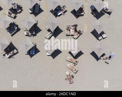 Immagini aeree di un drone della costa di Rethymno con la lunga spiaggia e i bar sull'isola di Creta. La gente è vista godendo il sole sotto l'ombrellone al bar della spiaggia o nuotando nel mare cristallino. Rethymno è una storica città balneare mediterranea sulla costa settentrionale di Creta, adagiato sul Mar Egeo con una popolazione di 40,000 persone. Una destinazione turistica con un porto storico veneziano e città, siti archeologici, spiagge sabbiose infinite, sport acquatici, belle taverne tradizionali e una grande varietà di hotel. Il turismo rimbalza indietro con prenotazioni che superano Foto Stock