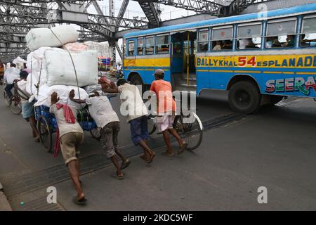 I lavoratori indiani spingono un furgone a caricare le merci attraverso il ponte Howrah a Kolkata, India, il 16,2022 giugno. (Foto di Debajyoti Chakraborty/NurPhoto) Foto Stock