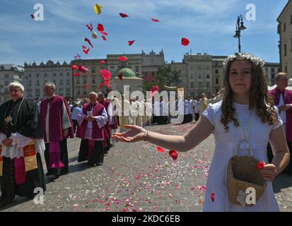 Una giovane ragazza vestita con i costumi della prima comunione sparse petali di fiori lungo la processione del Corpus Christi nella città vecchia di Cracovia. La festa del Corpus Domini, detta anche solennità del Santissimo corpo e sangue di Cristo, è una solennità liturgica cattolica che celebra la presenza reale del corpo e del sangue, dell'anima e della Divinità di Gesù Cristo negli elementi dell'Eucaristia. Giovedì 16 giugno 2022 a Cracovia, Polonia. (Foto di Artur Widak/NurPhoto) Foto Stock