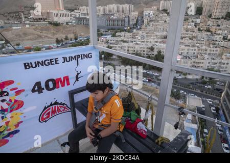 Nikan Zareian, un ragazzino iraniano di 11 anni, si siede su una piattaforma di 40 metri in attesa di esibirsi nella prima competizione acrobatica di bungee jumping del 15 giugno 2022 nel parco Adrenaline di Teheran nord-occidentale. La prima competizione acrobatica di bungee jumping in Iran si è tenuta all'Adrenaline Park, nella parte nordoccidentale di Teheran. (Foto di Morteza Nikoubazl/NurPhoto) Foto Stock