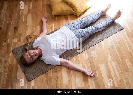 Donna caucasica matura che riposa dopo la pratica di yoga nella savasana Foto Stock