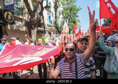 I manifestanti detengono una bandiera gigante della Tunisia mentre fanno il segno della vittoria durante una marcia di protesta tenuta dal fronte Nazionale della salvezza a Tunisi, in Tunisia, il 19 giugno, 2022 per chiedere il boicottaggio del referendum su una nuova costituzione annunciato dal presidente tunisino Kais Saied e che si terrà il 25 luglio. I dimostranti hanno protestato anche contro Kais Saied e contro le misure eccezionali che ha adottato dal luglio 2021, e hanno chiesto la caduta di quella che chiamano dittatura. (Foto di Chardy ben Ibrahim/NurPhoto) Foto Stock