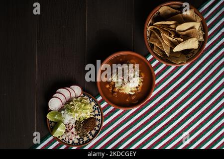 Una vista dall'alto di Pozole Rojo (maiale messicano e stufato Hominy), tortilla patatine e un piatto con verdure Foto Stock