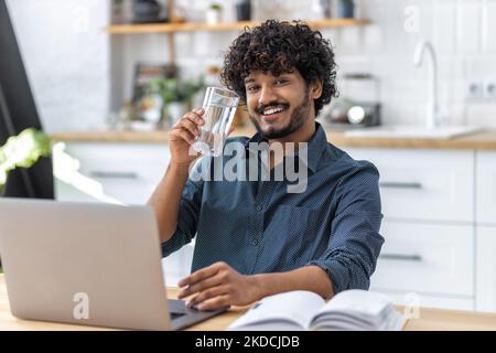 Felice imprenditore o freelance riuscito dell'uomo asiatico che tiene il vetro dell'acqua pulita che funziona nel paese Foto Stock