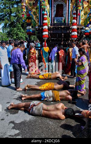 I devoti indù del Tamil eseguono il rituale angapradakshinam (come atto di penitenza) durante il Vinayagar Ther Thiruvizha Festival in un tempio indù del Tamil in Ontario, Canada, il 23 luglio 2016. Il rituale di Angapradakshinam richiede ai devoti di tenere le noci di cocco di puja mentre si rotolano a terra dietro il grande carro di legno che porta l'idolo di Lord Vinayagar durante la stravagante processione dei carri. (Foto di Creative Touch Imaging Ltd./NurPhoto) Foto Stock