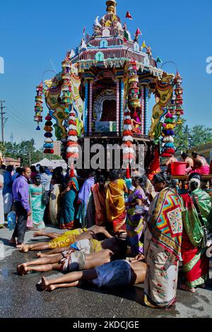 I devoti indù del Tamil eseguono il rituale angapradakshinam (come atto di penitenza) durante il Vinayagar Ther Thiruvizha Festival in un tempio indù del Tamil in Ontario, Canada, il 23 luglio 2016. Il rituale di Angapradakshinam richiede ai devoti di tenere le noci di cocco di puja mentre si rotolano a terra dietro il grande carro di legno che porta l'idolo di Lord Vinayagar durante la stravagante processione dei carri. (Foto di Creative Touch Imaging Ltd./NurPhoto) Foto Stock