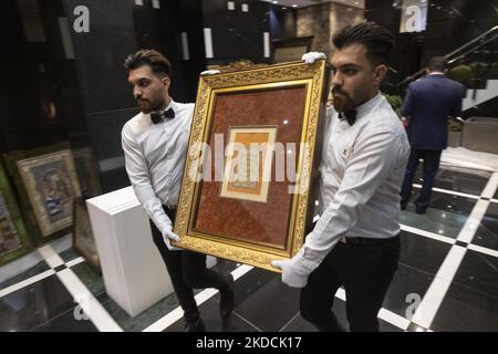 Due dipendenti che riportavano una calligrafia incorniciata al backstage durante l'asta del mondo islamico e iraniano del 7th, tenuta dalla Melli (National) Auction House in un centro conferenze nel nord di Teheran il 24 giugno 2022. (Foto di Morteza Nikoubazl/NurPhoto) Foto Stock