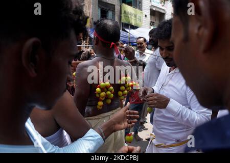 Un devoto indù con il suo corpo trafitto da aghi attaccati ai limoni partecipa ad una processione religiosa per celebrare il festival 'Muthu Mariamman' a Nuova Delhi, India, il 26 giugno 2022. Il festival, celebrato in India e nel subcontinente dell'Asia meridionale, dove si trovano importanti comunità tamil, presenta una delle più estreme manifestazioni di devozione religiosa al mondo. (Foto di Mayank Makhija/NurPhoto) Foto Stock