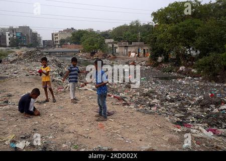 I bambini giocano lungo uno scarico di liquame aperto riempito di plastica e sporcizia in una baraccopoli a Nuova Delhi, India il 29 giugno 2022. L'India sta applicando un divieto sugli articoli in plastica monouso, che hanno un basso potenziale di utilità ed un alto potenziale di lettering, in tutto il paese dal 1 luglio 2022. (Foto di Mayank Makhija/NurPhoto) Foto Stock