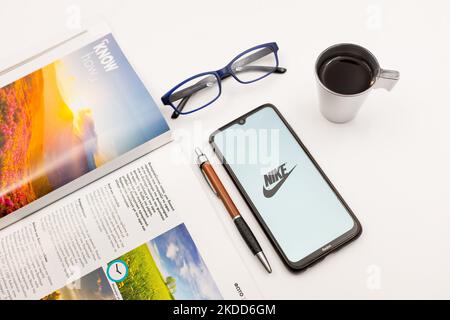 In questa foto, il 4 luglio 2022, un logo Nike viene visualizzato sullo schermo di uno smartphone su una scrivania accanto a un bar, una penna, occhiali e una rivista ad Atene, in Grecia. ( Foto Illustrazione di Nikolas Kokovlis/NurPhoto) Foto Stock
