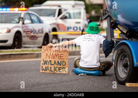 Un membro della Extinction Rebellion DC mostra un cartello a sostegno di Jayland Walker mentre è incatenato a una barca fuori dalla sede della Washington gas Light. Walker è l'uomo nero sparato 60 volte e ucciso dalla polizia ad Akron, OH. La protesta fa parte della campagna "End methane, electrify DC" di XRDC. Il gruppo sta protestando per l'espansione delle infrastrutture di combustibili fossili e per il ruolo dell'azienda nelle perdite di metano che attualmente colpiscono DC. Il metano è il gas serra più potente che guida il riscaldamento globale, 80 volte più efficace nel intrappolare il calore rispetto al biossido di carbonio nel corso di 20 anni. (Foto b Foto Stock