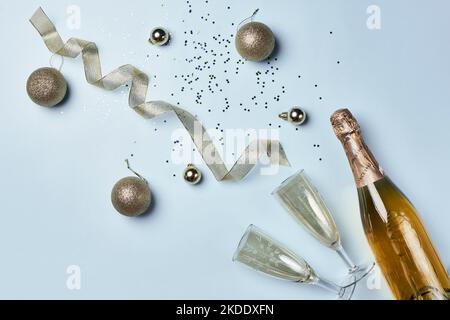 lo champagne viene versato da una bottiglia con confezioni sparse intorno ad essa su una superficie azzurro, circondata da confezione Foto Stock