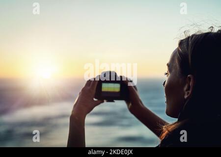 Il suo paesaggio perfetto. Ripresa da dietro di una giovane donna che scatta foto con la sua fotocamera all'aperto. Foto Stock