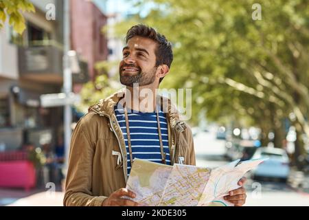 Mantenere la calma e viaggiare su. Un turista felice utilizzando una mappa per esplorare una città straniera da solo. Foto Stock