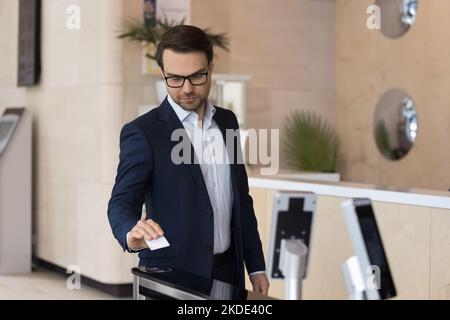 Uomo d'affari che utilizza la pass card apre cancelli automatici in un ufficio moderno Foto Stock