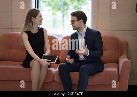 Due colleghi millenari si incontrano nella hall dell'ufficio per una piacevole conversazione Foto Stock