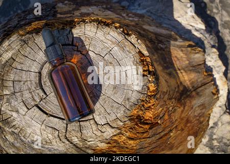 Bottiglia di olio cosmetico naturale per la cura del corpo e della pelle, aromaterapia su uno sfondo di legno. Estratto di oli naturali, concetto di prodotti medici. Foto di alta qualità Foto Stock