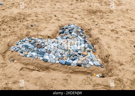 Un cuore fatto di ciottoli trovato a Fistral Beach in Cornovaglia, Regno Unito Foto Stock
