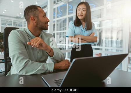 Due colleghi multietnici che parlano mentre lavorano insieme in un ufficio moderno Foto Stock