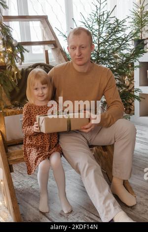 Papà e sua figlia in una magica atmosfera natalizia. Il concetto di relazioni familiari e celebrazioni per il nuovo anno. Foto Stock