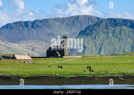 L'ex chiesa di San Edoardo sull'isola di Sanday, dall'isola di canna, Scozia, Regno Unito. Dietro si trovano le montagne dell'Isola di Rum. Foto Stock