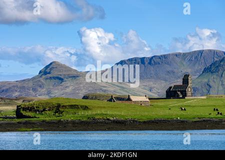 L'ex chiesa di San Edoardo sull'isola di Sanday, dall'isola di canna, Scozia, Regno Unito. Dietro si trovano le montagne dell'Isola di Rum. Foto Stock