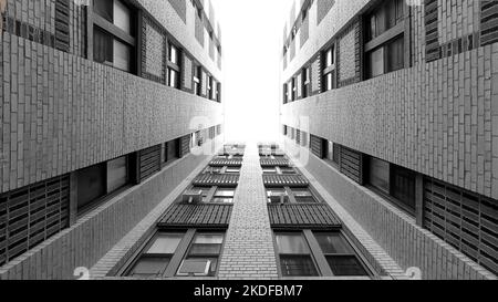 Architettura astratta in bianco e nero. Guardando verso l'alto nel cortile di un edificio del Bronx verso un cielo sovraesposto. grandangolo da 10mm mm, 16:9 Foto Stock