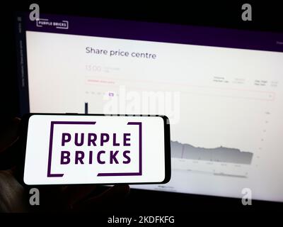 Persona che tiene il telefono mobile con il logo della società immobiliare Purplebricks Group plc sullo schermo di fronte alla pagina web. Messa a fuoco sul display del telefono. Foto Stock