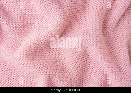 Primo piano del tessuto di lana lavorato a maglia in filato di viscosa. Tessuto a maglia in lana grattato di colore rosa brillante. Stropicciate a maglia astratta Foto Stock