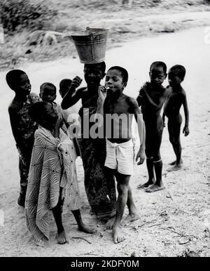 Un bambino che fuma una sigaretta con un gruppo di amici vicino ad Axim in Ghana, nel 1959 Foto Stock