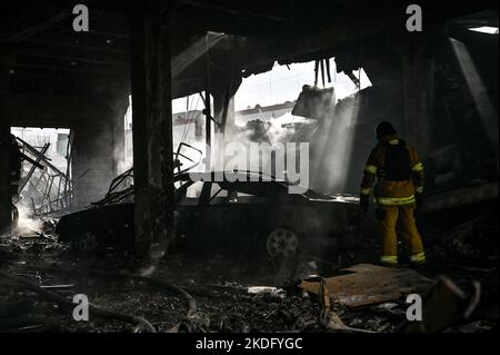 ZAPORIZHZHZHIA, UCRAINA - 6 NOVEMBRE 2022 - Un soccorritore si trova davanti ad un'auto bruciata durante uno sforzo di risposta ad un attacco missilistico russo che lef Foto Stock