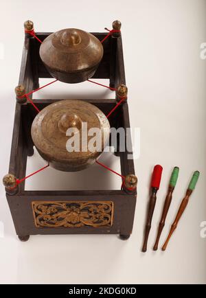 Kethuk Kempyang, uno strumento musicale indonesiano utilizzato nel gamelan giavanese. Gong in bronzo bilanciati su corda con una cornice decorativa in legno. Con Foto Stock