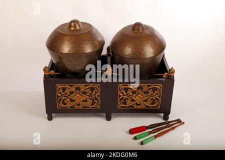 Bonang, uno strumento musicale indonesiano utilizzato nel gamelan giavanese. Gong in bronzo bilanciati su corda con una cornice decorativa in legno. Con fruste. Foto Stock