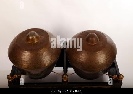 Bonang, uno strumento musicale indonesiano utilizzato nel gamelan giavanese. Gong in bronzo bilanciati su corda con una cornice decorativa in legno. Con fruste. Foto Stock