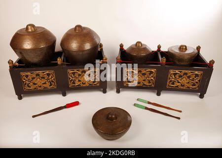 Bonang, uno strumento musicale indonesiano utilizzato nel gamelan giavanese. Gong in bronzo bilanciati su corda con una cornice decorativa in legno. Con fruste. Foto Stock