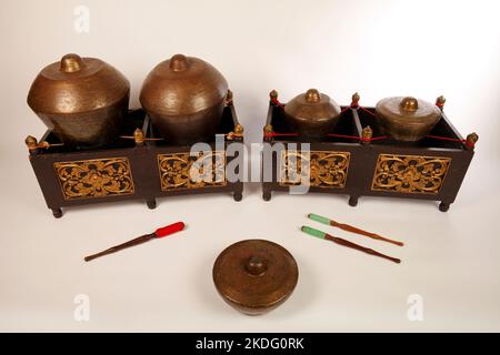 Bonang, uno strumento musicale indonesiano utilizzato nel gamelan giavanese. Gong in bronzo bilanciati su corda con una cornice decorativa in legno. Con fruste. Foto Stock