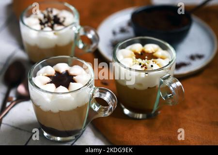 Piccole tazze con un dessert a tre strati di caffè e caramello. Delizioso budino in tazze di vetro. Foto Stock