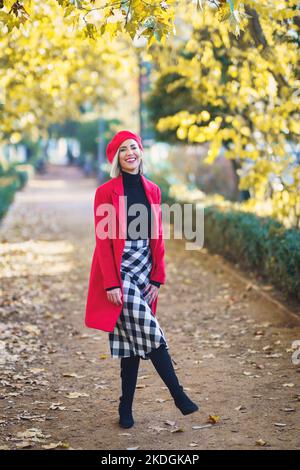 Donna allegra in piedi nel parco autunnale Foto Stock