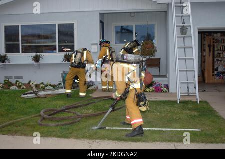 Il vigile del fuoco di San Diego Fire-Rescue pulisce gli attrezzi dopo aver lavorato un incendio strutturale nella sezione Kearny Mesa di San Diego Foto Stock