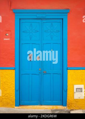 Porta blu su sfondo arancione e giallo, caratteristica della città di Jerico, Antioquia, Colombia Foto Stock