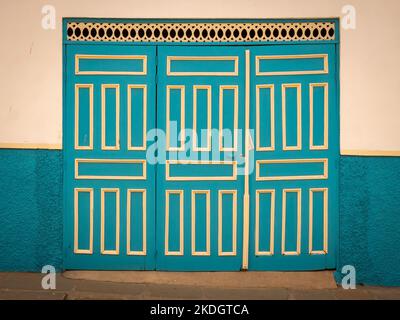 Porta di garage blu e gialla su sfondo bianco, caratteristica della città di Jerico, Antioquia, Colombia Foto Stock