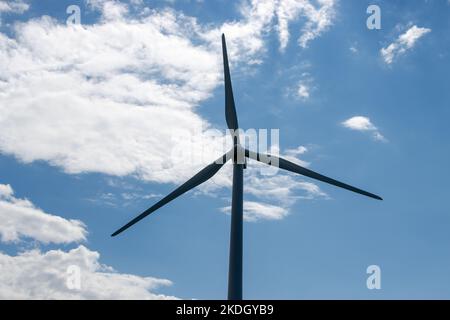 Silhouette vista di una turbina eolica su un cielo nuvoloso blu a Gaspesie, Quebec, Canada Foto Stock