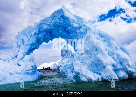 Un iceberg di ghiaccio blu in Antartide con un interessante foro / forma ad arco Foto Stock