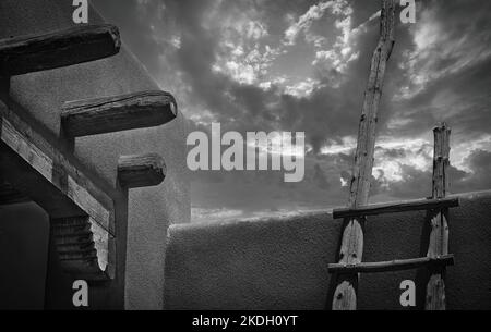 Tradizionale scala in legno su architettura sudoccidentale di Adobe con piogge pomeridiane in movimento. Foto Stock