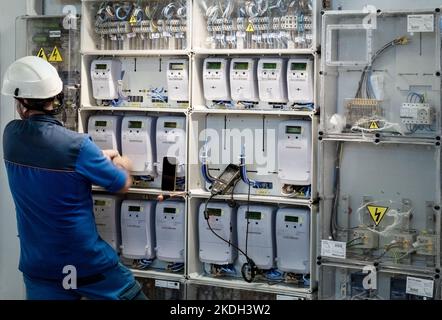 Elettricista durante il lavoro di installazione in stanza con lettori di contatori elettrici. Foto Stock